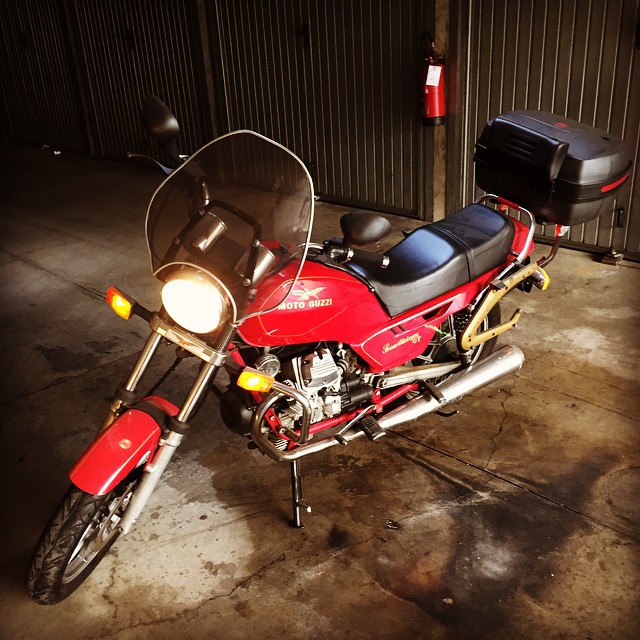 a motorcycle parked in a garage with another bike nearby
