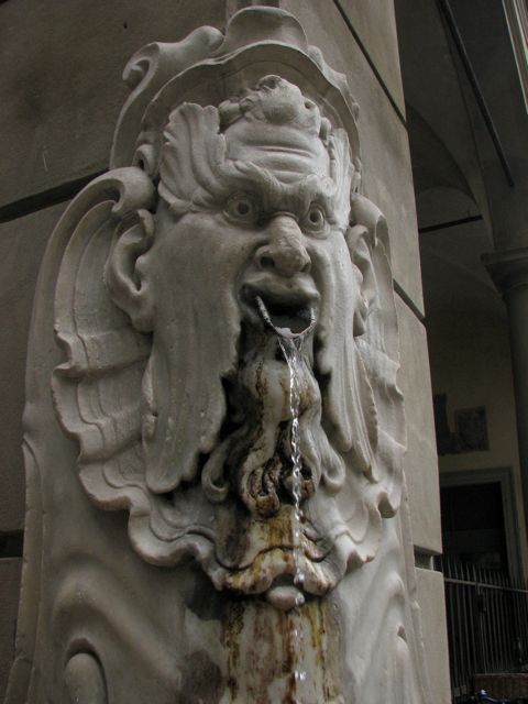 a water fountain with a face on the wall
