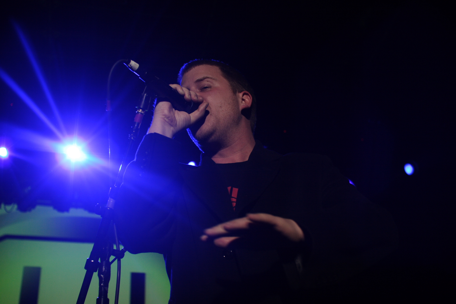 man singing into a microphone at the top of a stage