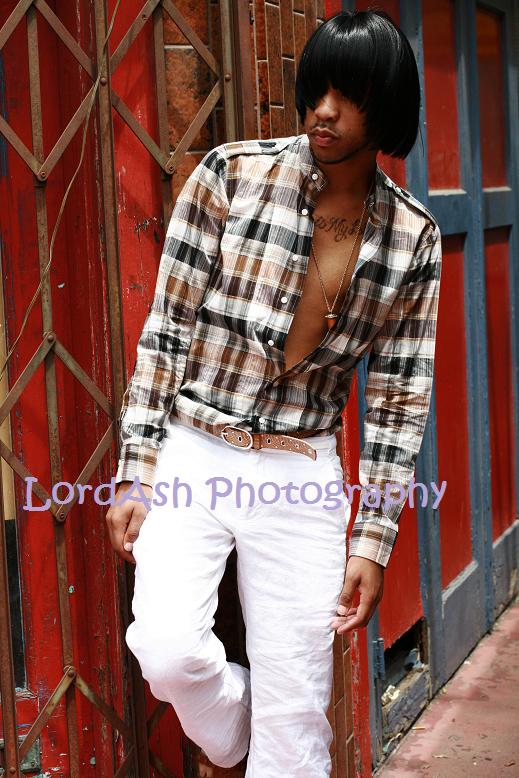 a young black male standing by a brick building