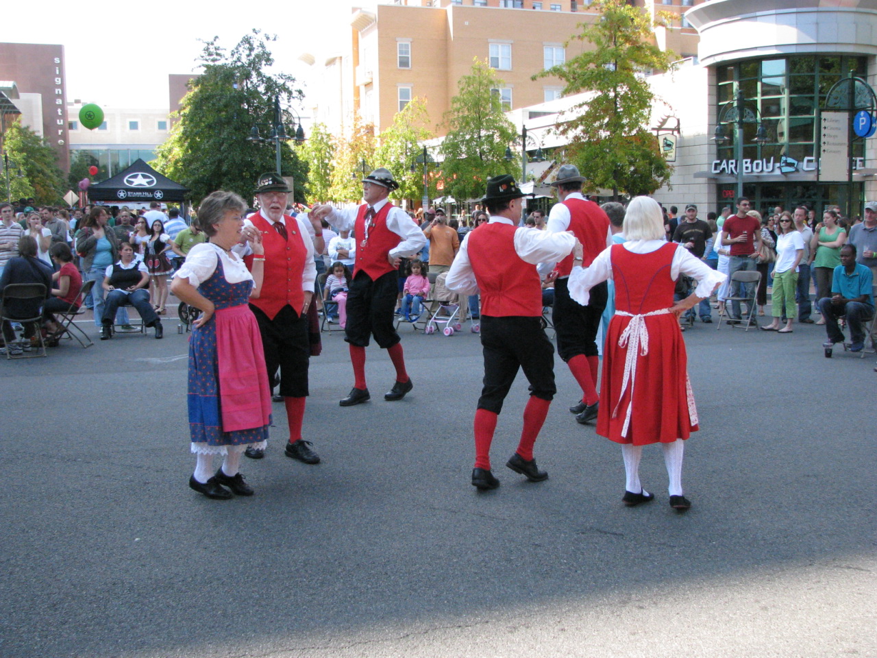 a crowd watches two men in colonial garb dance in front of a crowd