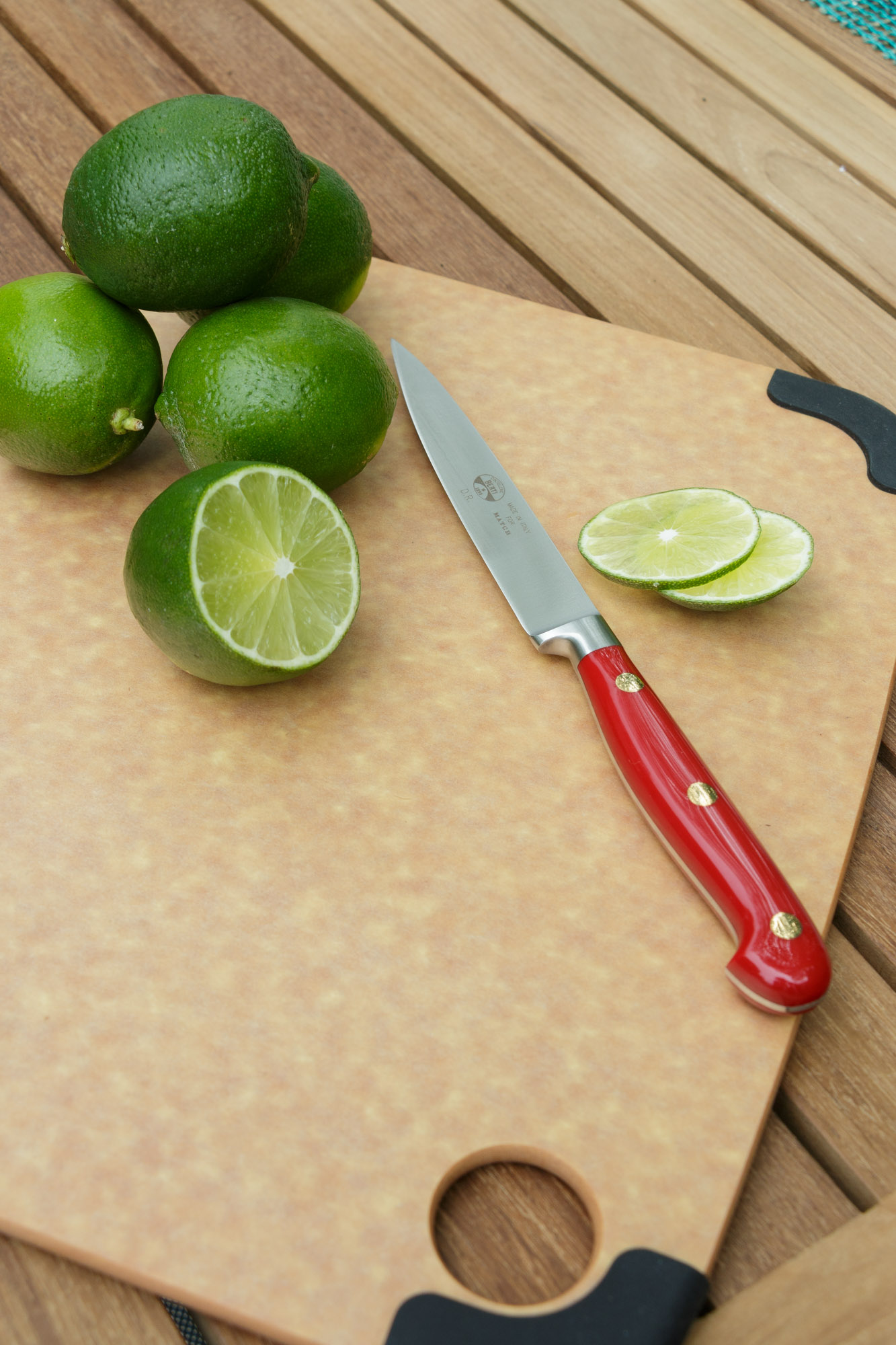 a  board on a table topped with limes and a knife