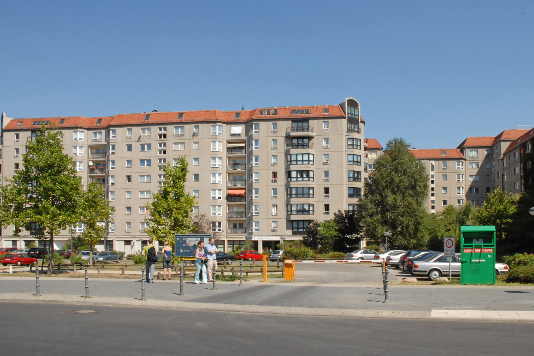 a parking lot with trees and buildings in the background