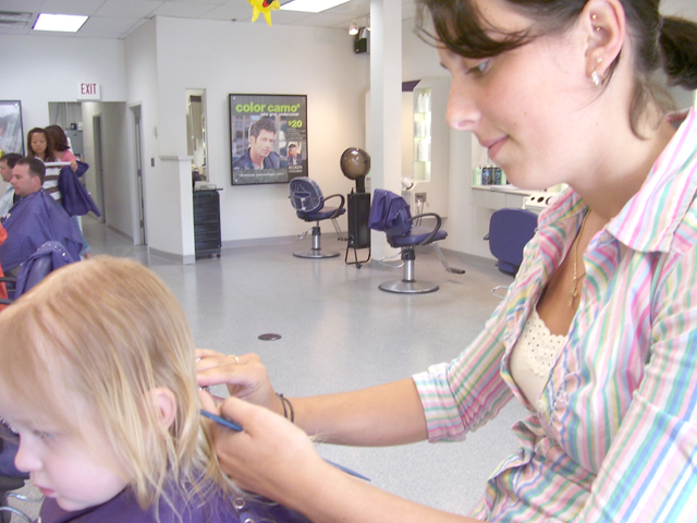 a woman brushing a child's hair in a hair salon