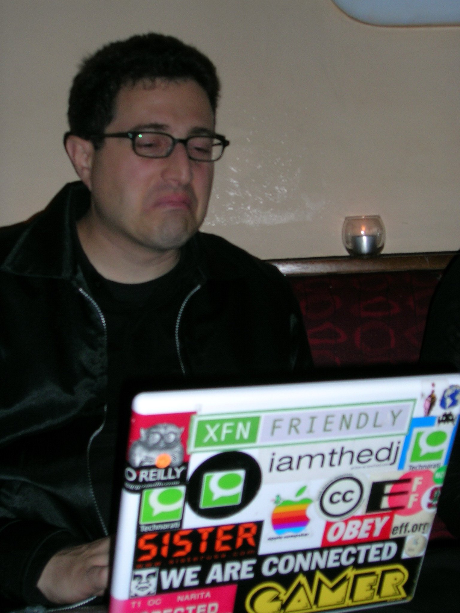 a man in black jacket sitting in front of a laptop