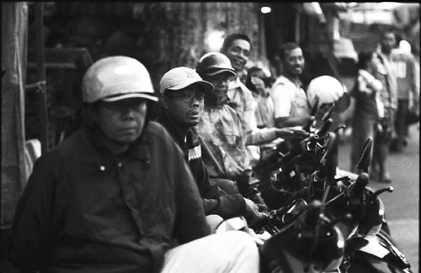 black and white image of men sitting on a motorbike