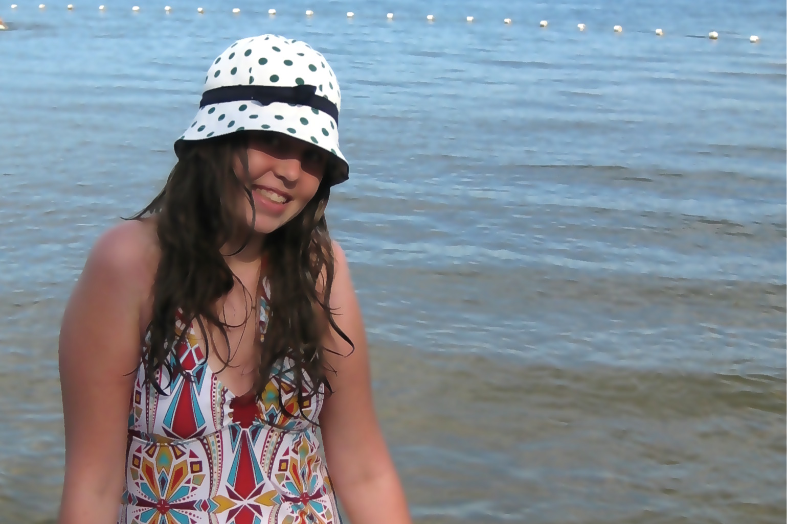 young lady at a beach standing next to water