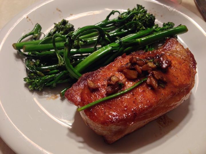 a white plate with some meat and green broccoli on it