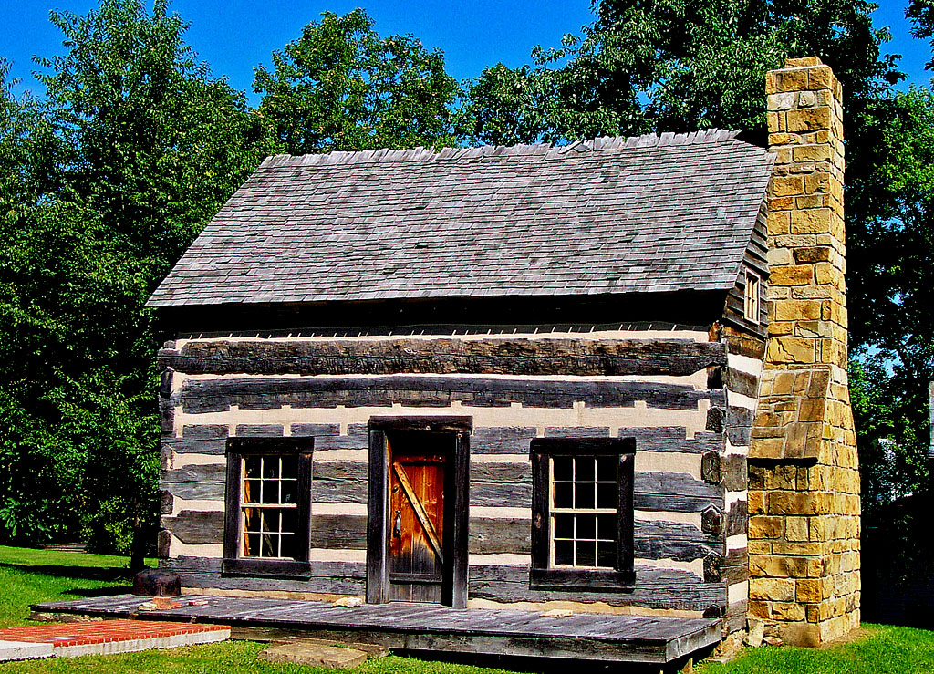 a log cabin sits next to an old fashioned stove