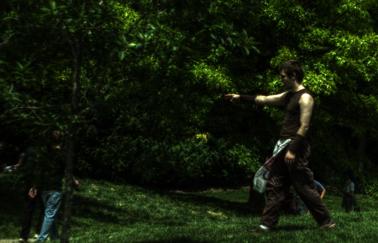 a man holding soing in his hand while standing next to some trees