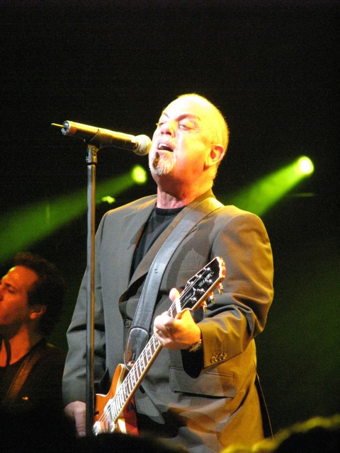 a man standing in front of a microphone and holding a guitar