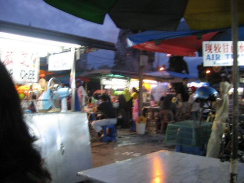 a market with umbrellas and people sitting on benches