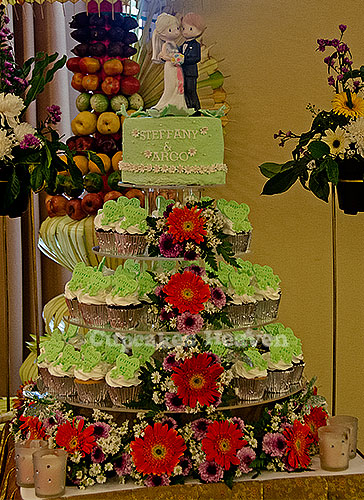 a display table holding cupcakes and other colorful cakes