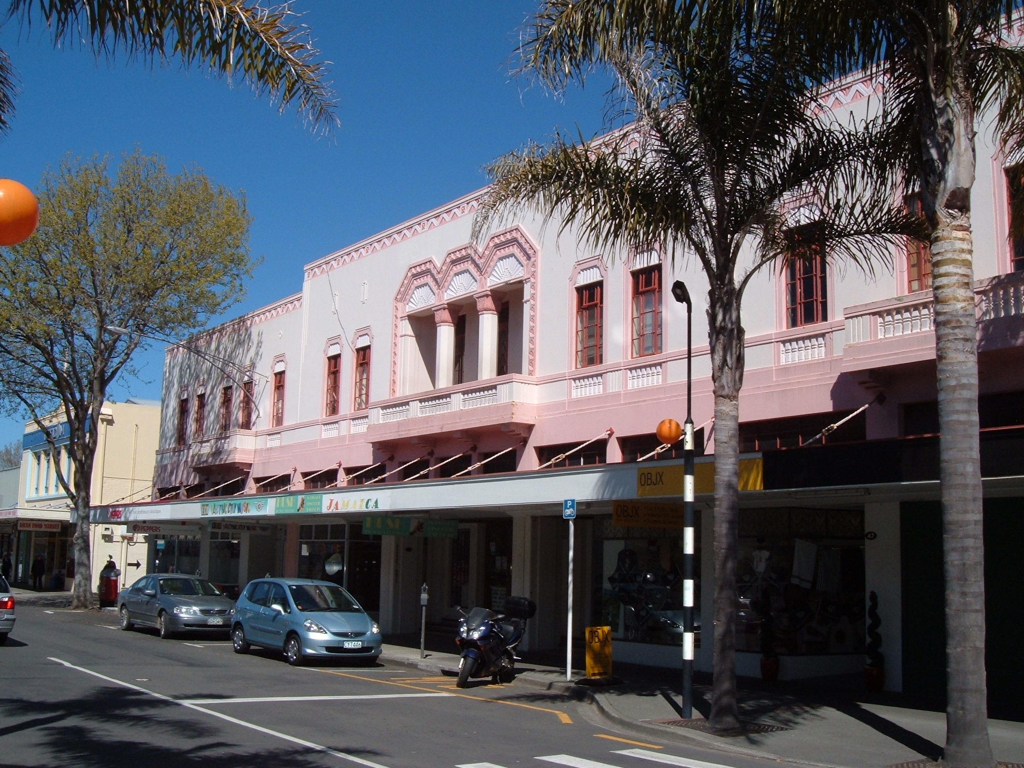 pink building next to a street with traffic lights and street signs