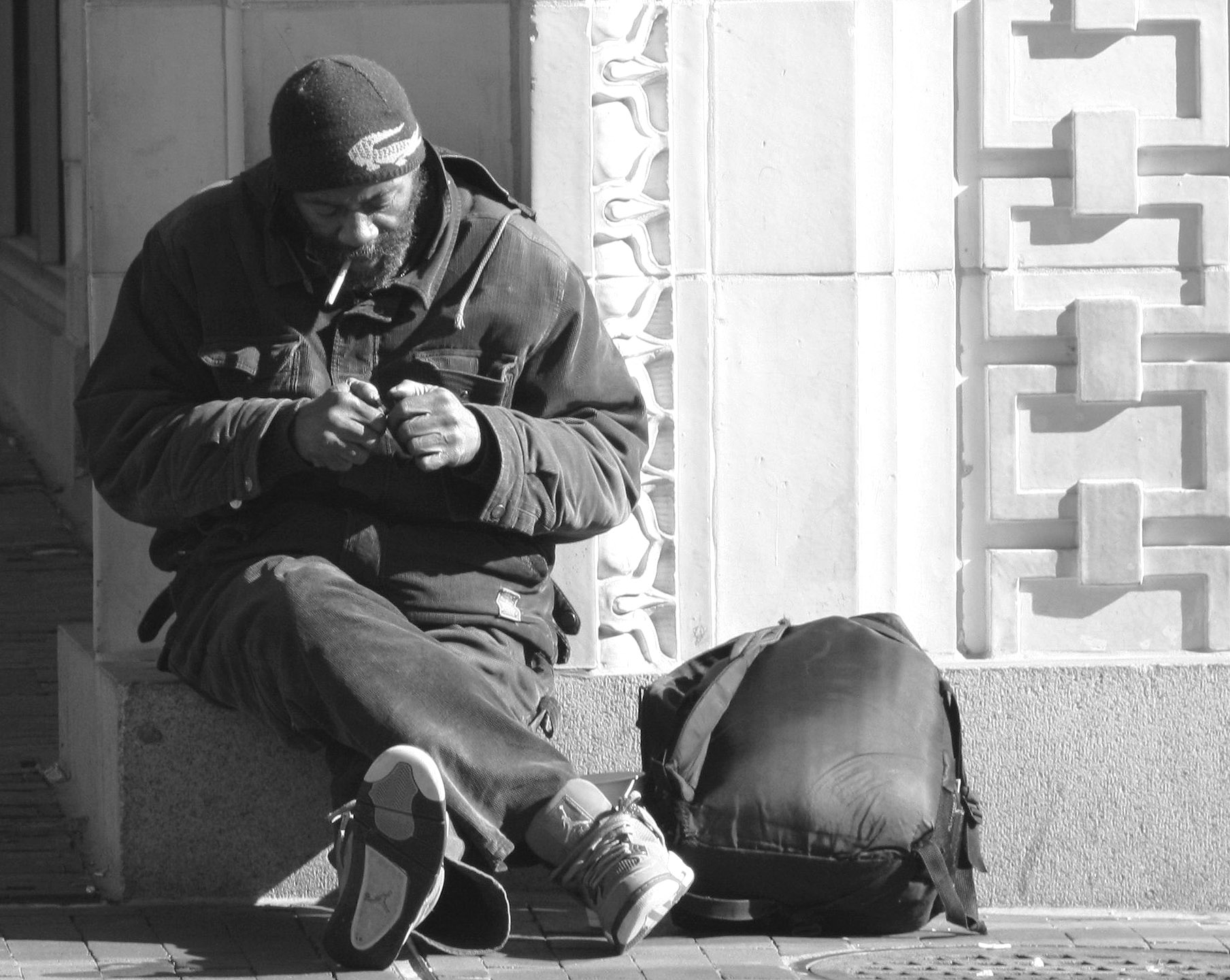 a man sitting on the ground smoking a cigarette