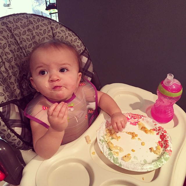 the baby is eating her birthday cake at her high chair