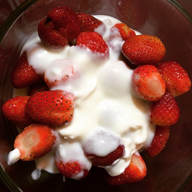 a bowl of strawberries and cream with a napkin