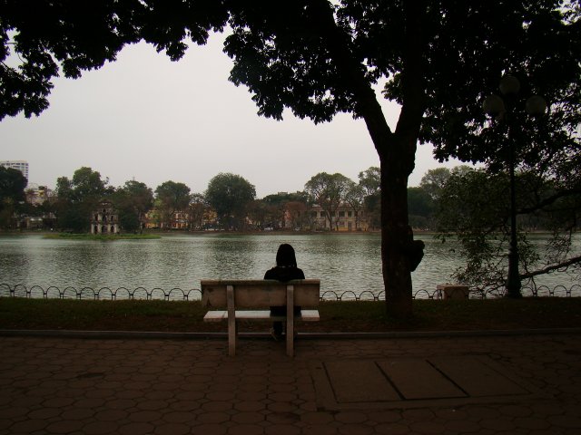 a person sitting on a bench in front of a lake