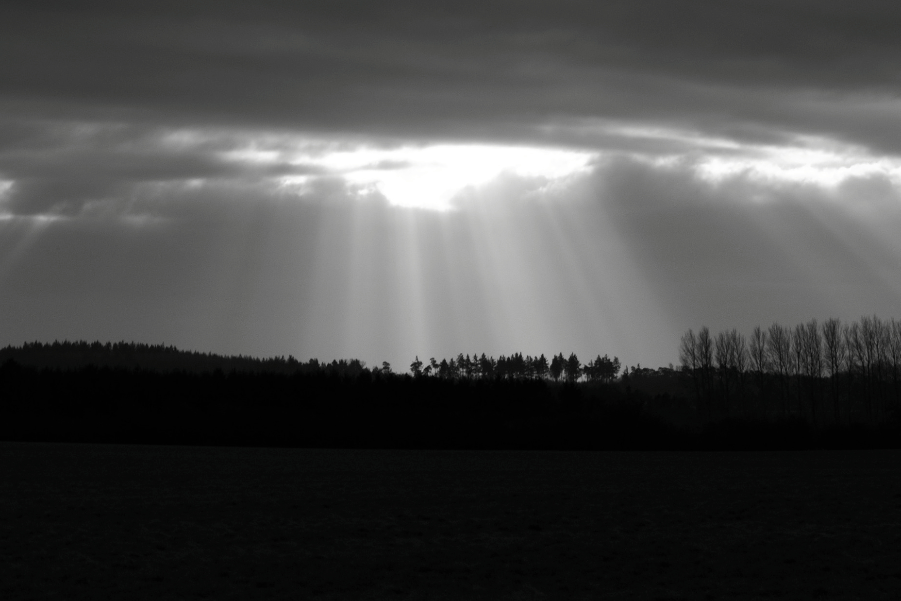 the sun's rays shine brightly through a dark, cloudy sky