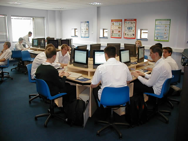 an office cubicle with some men sitting at computers