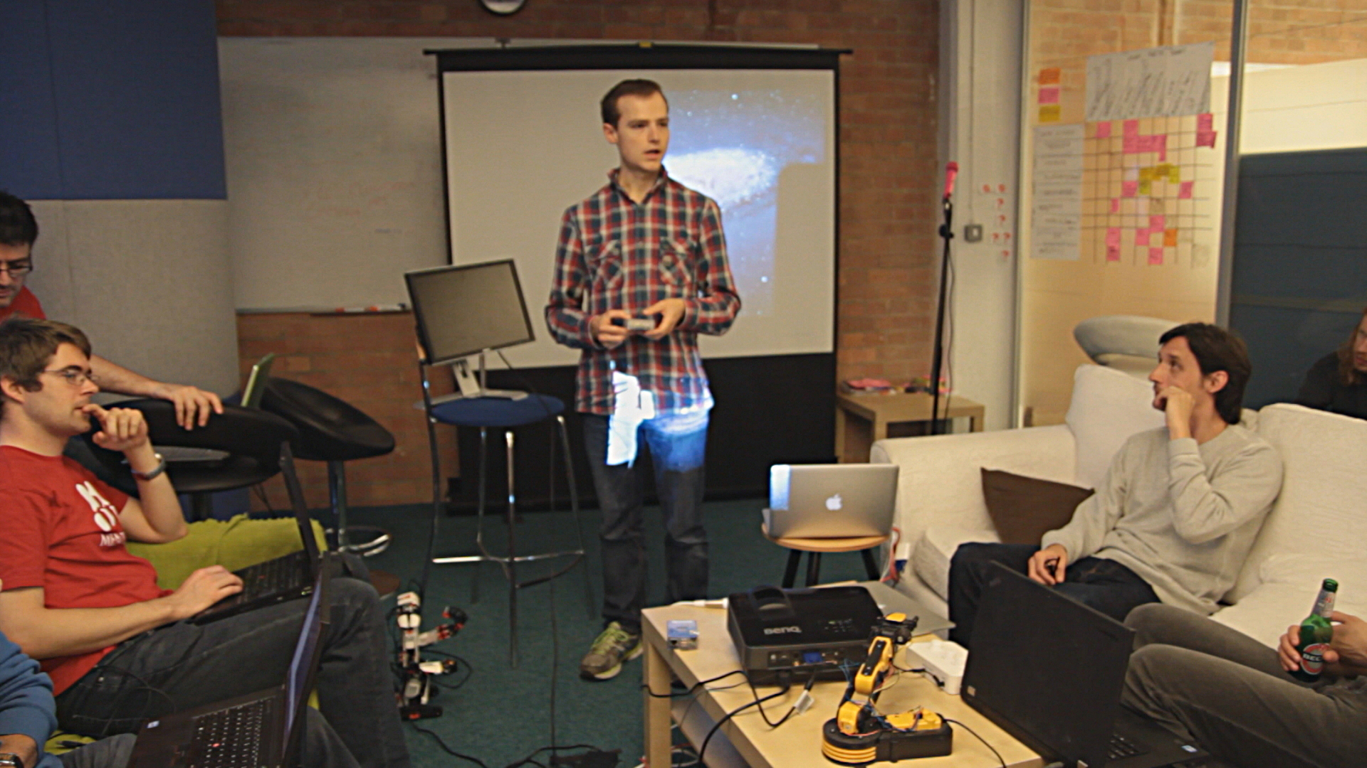 four young men are in the living room with a projector