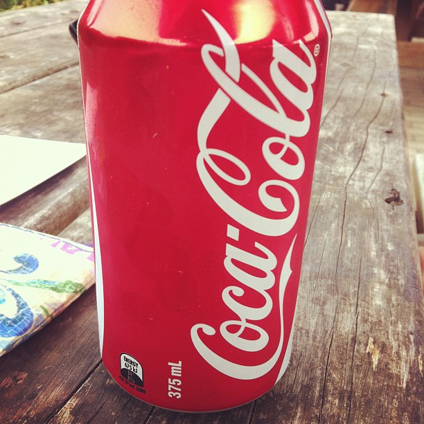 a can of coke sitting on top of a wooden table