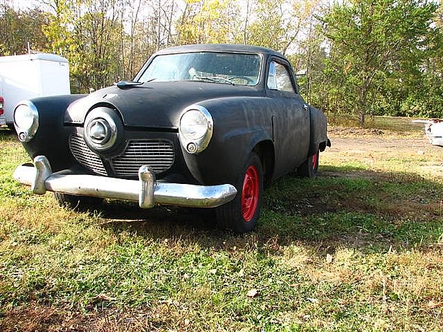 this old black car is parked outside in the grass