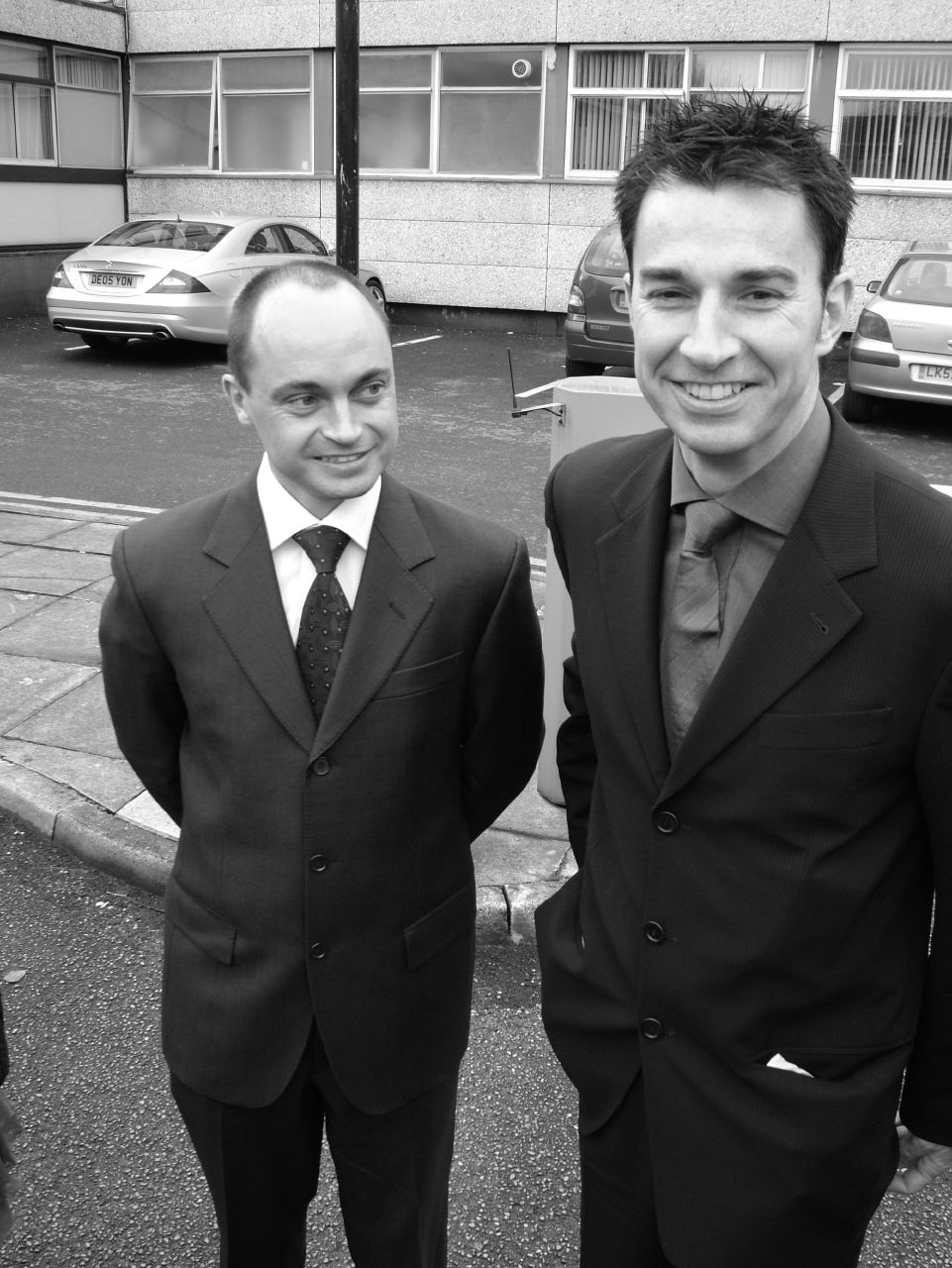 two well dressed men stand together near the street