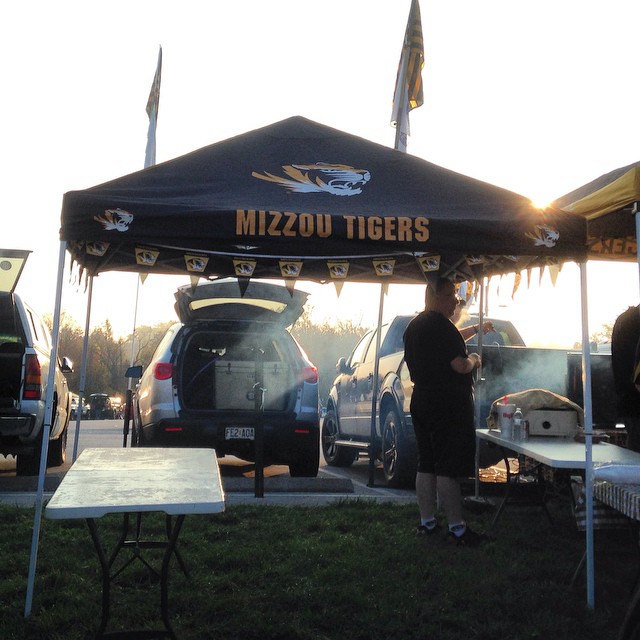 a man stands under a black tent with two tigers on it