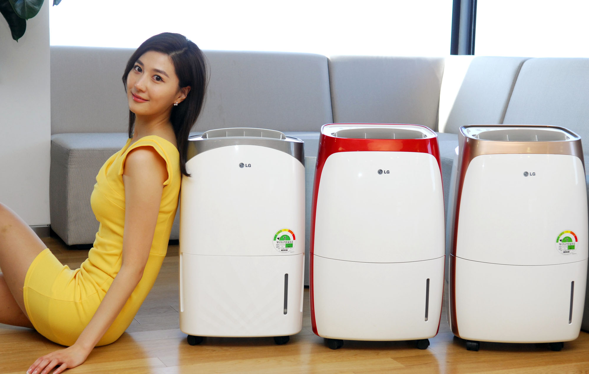 an asian woman sitting next to four portables that look like air purifiers
