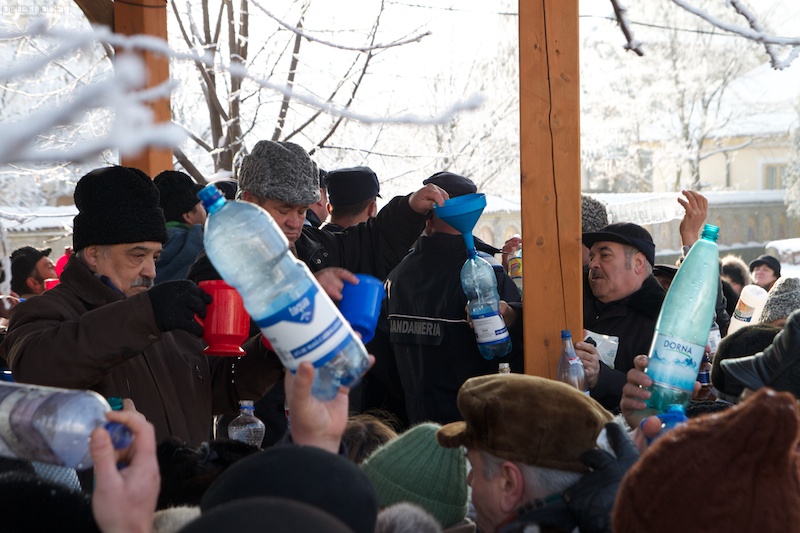 many people holding water bottles with a white snow covered tree in the background