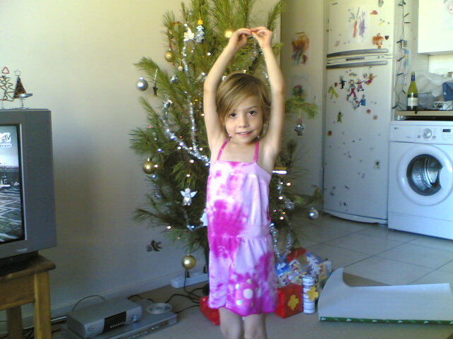 a girl wearing a pink dress stands in front of a christmas tree