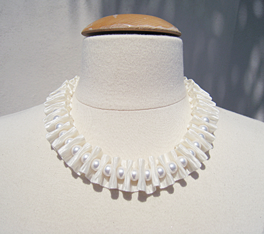 a white pearl necklace set on a mannequin