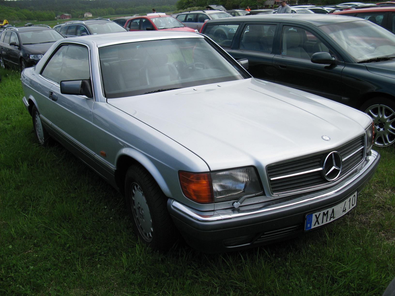 a row of cars parked on top of a lush green field