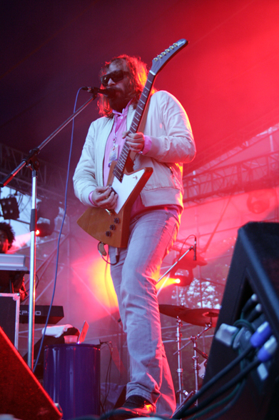 a man standing on a stage playing an electric guitar