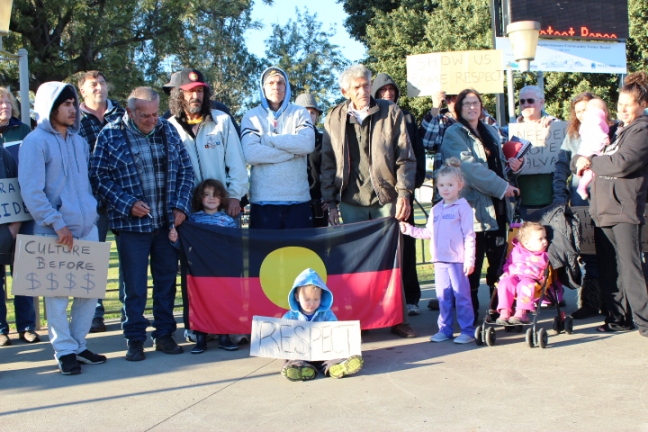 a large crowd of people are in front of a building holding up posters