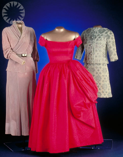 two dresses and coat on display in front of a blue background