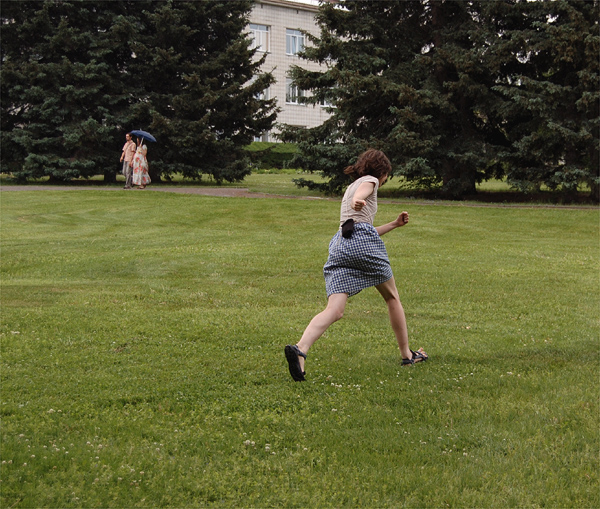 a man running across a green field in shorts