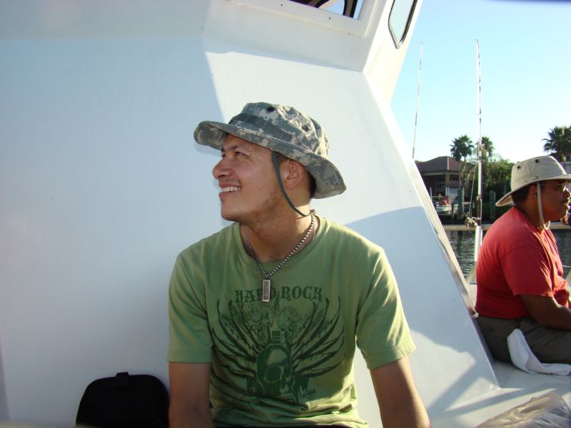 the man wearing a green shirt and a hat is sitting on a boat