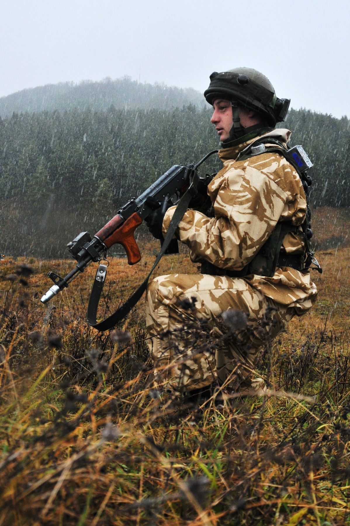 a man kneeling in the rain with a gun
