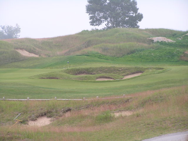 the hole 7 at a golf course has grass, dirt and sand