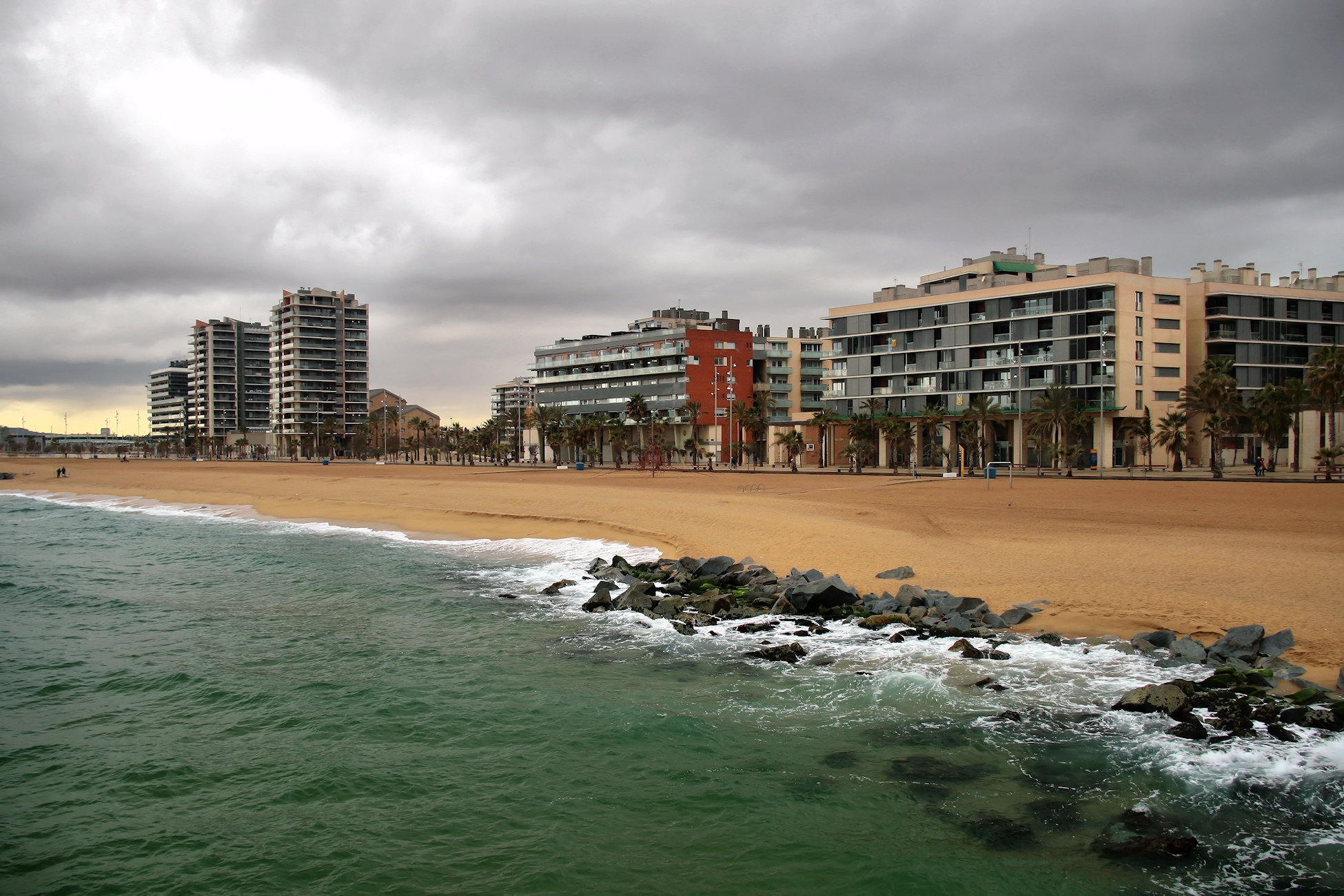 a long beach sits next to buildings and a large body of water