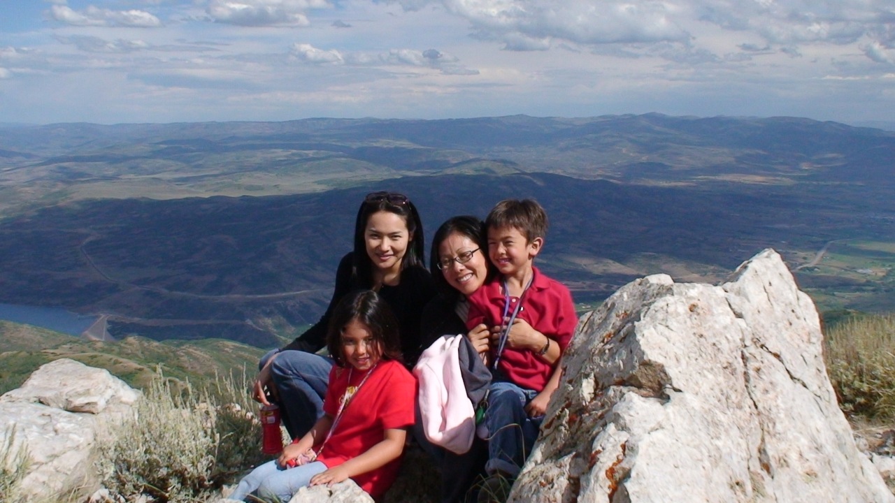 three adults and two children sitting on rocks overlooking the valley