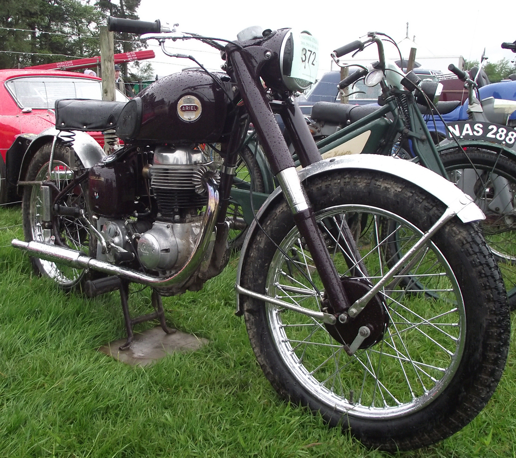 an antique motorcycle sitting on some grass in the background