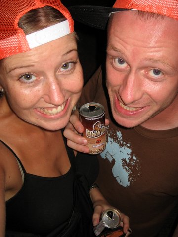 two people pose for the camera while holding a can of beer