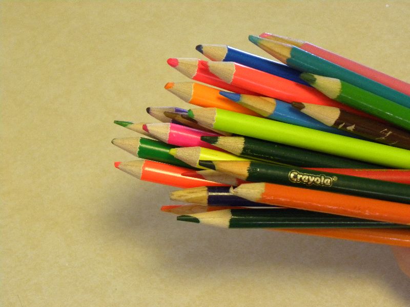 a pile of multi colored pencils sitting in a man's hand