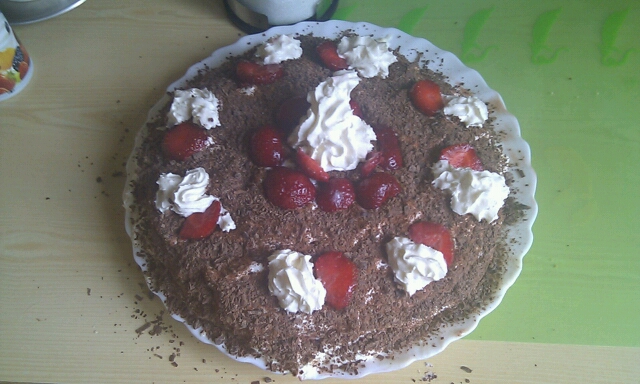 a cake covered in chocolate and covered with whipped cream and fresh strawberries