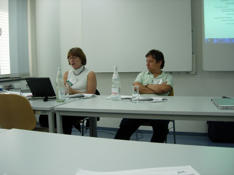 three people sitting at tables looking toward a projector screen