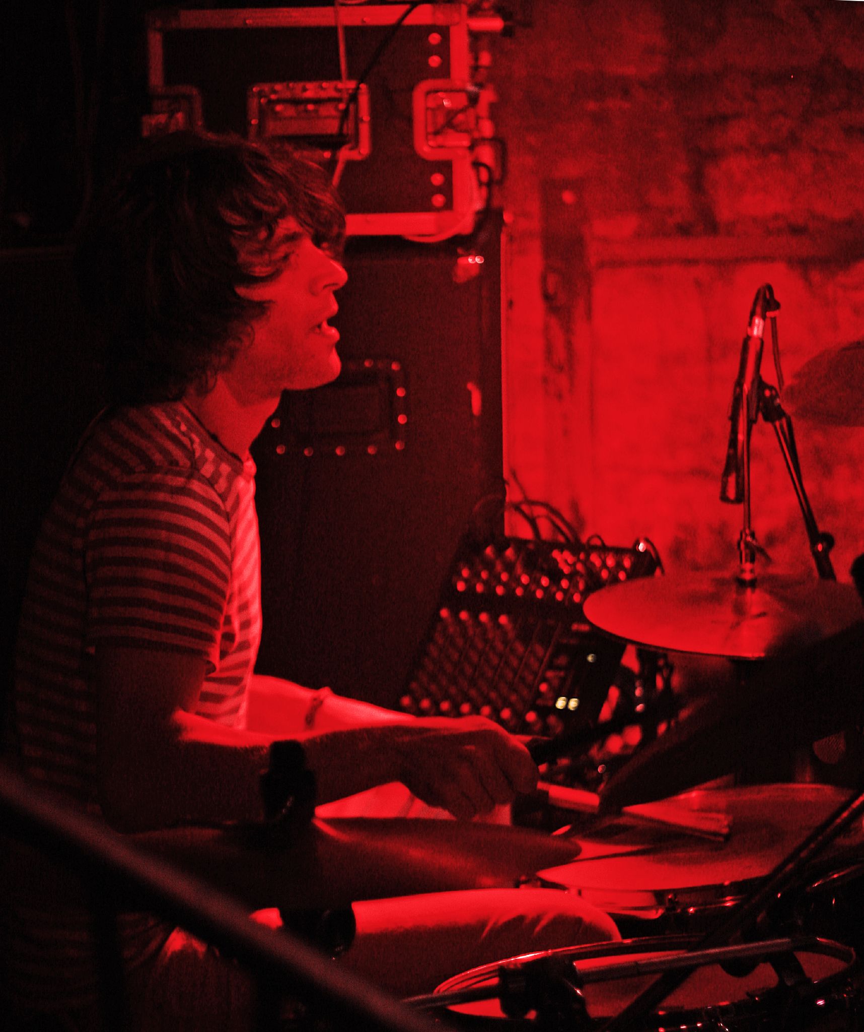 a woman with headphones sitting on a drum set in front of a microphone