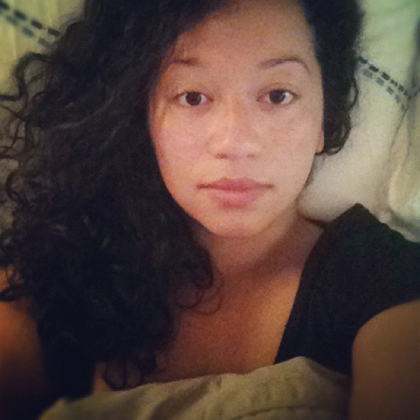 a woman laying in bed with curly hair